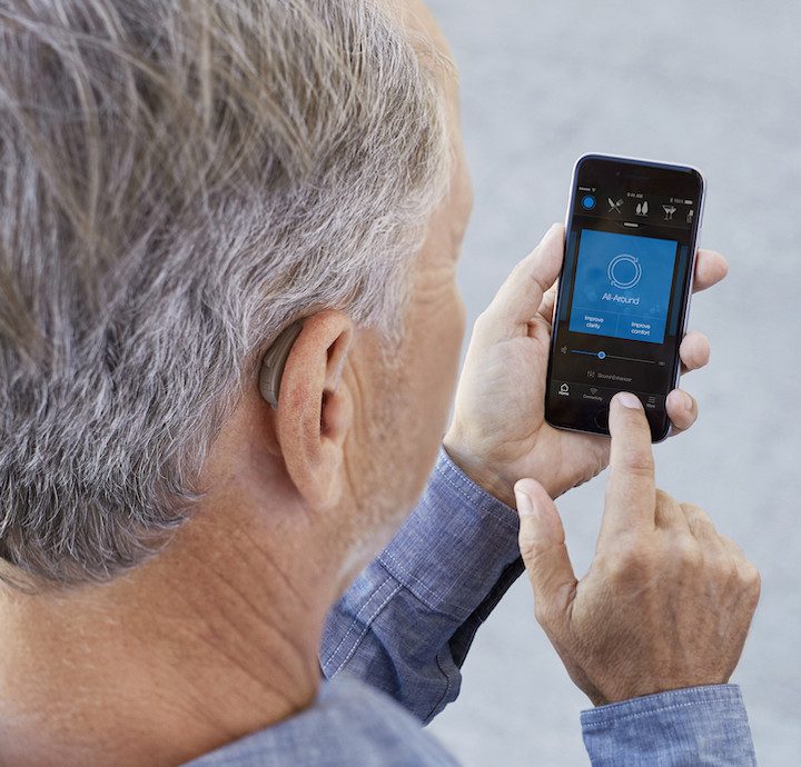 Male Adjusting His Hearing Aid Devices Using A Companion App